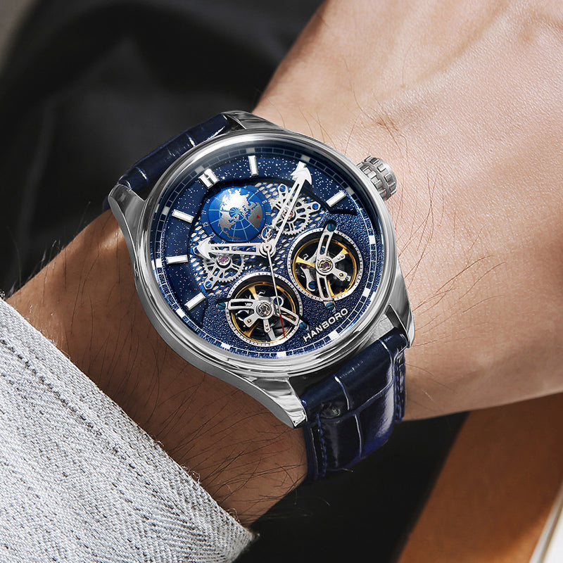 Luxury blue skeleton chronograph watch with world map dial and leather strap on a man's wrist